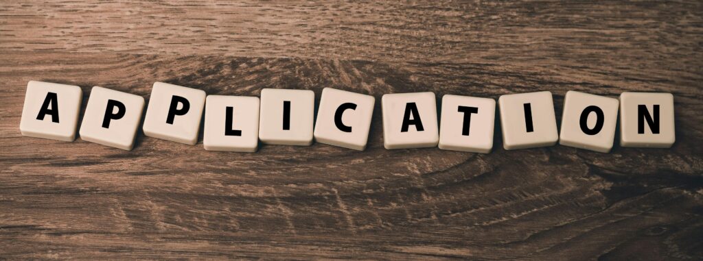 Scrabble letter tiles spelling 'application' on a wooden surface.